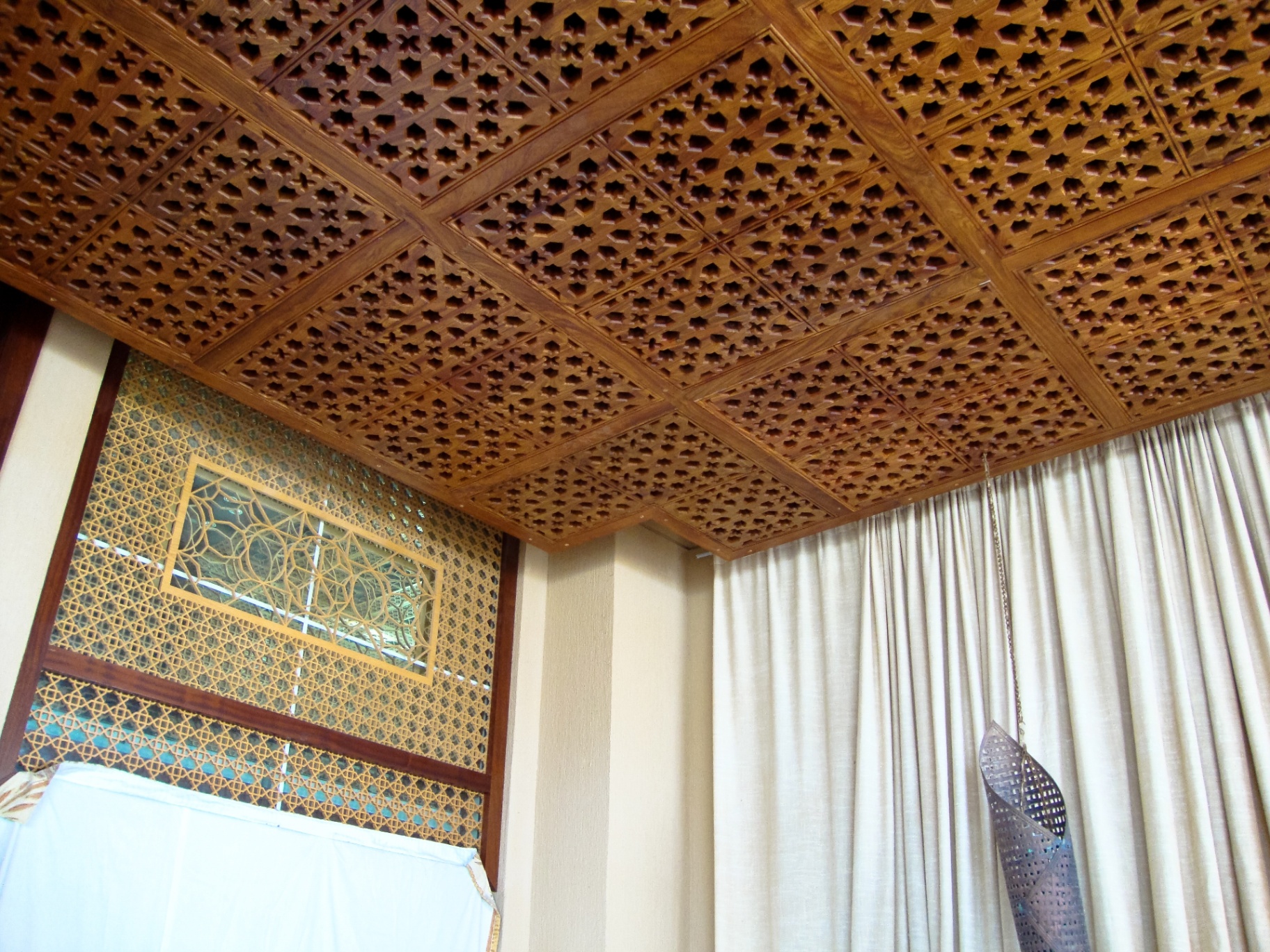 Traditional wooden mashrabiya ceiling with intricate Islamic star patterns and decorative wall panels