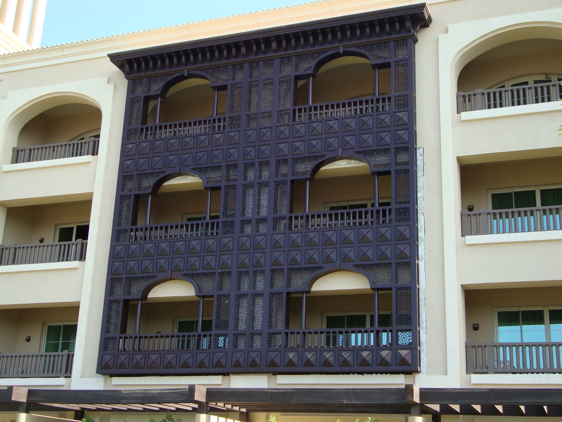 Large scale architectural mashrabiya facade with arched openings and geometric patterns