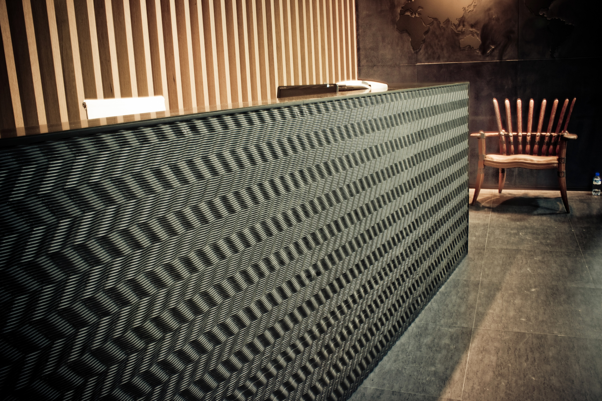 Modern reception desk with CNC cut woven pattern cladding in dark finish