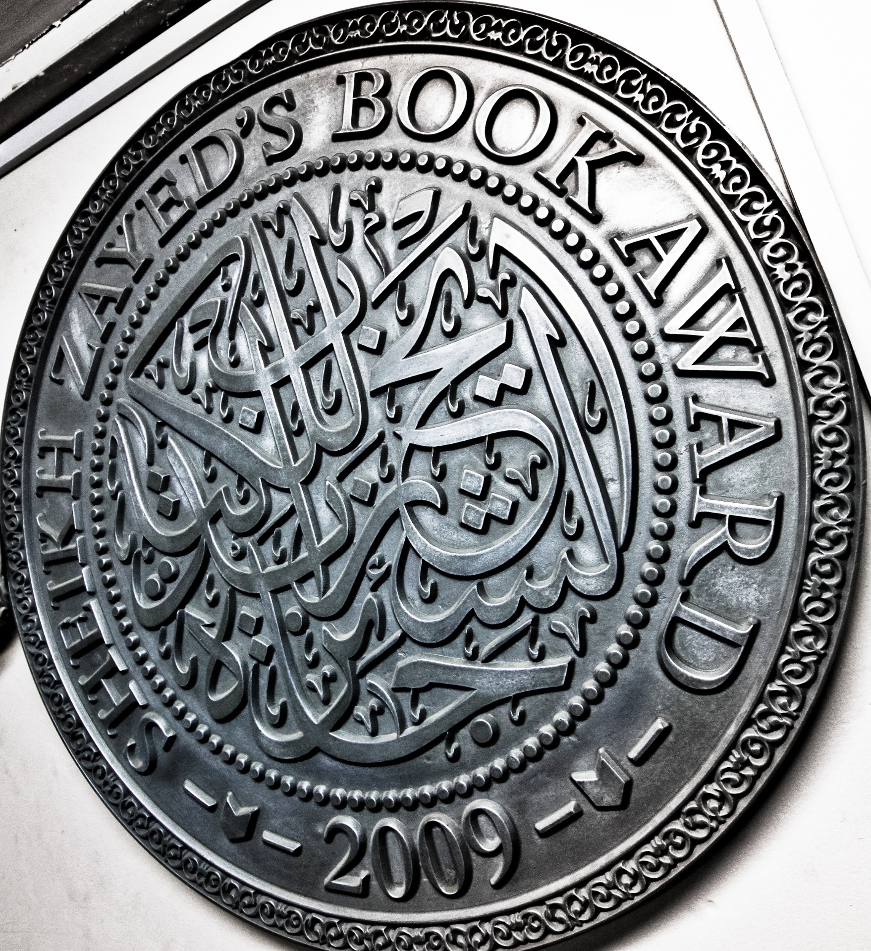 CNC engraved metal medallion with Arabic calligraphy and ornate border design