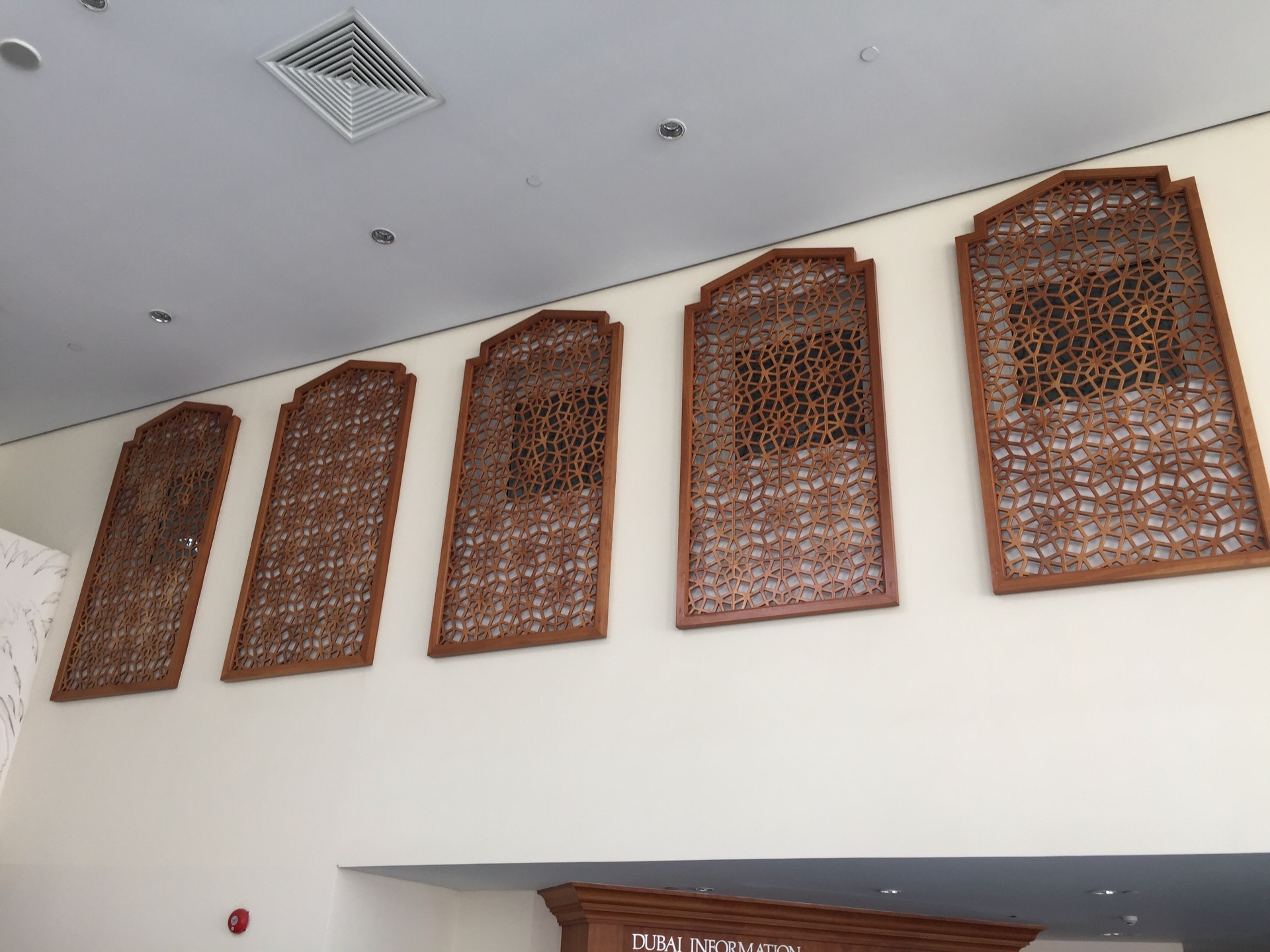 Series of wooden mashrabiya wall panels with Islamic geometric patterns in arched frames